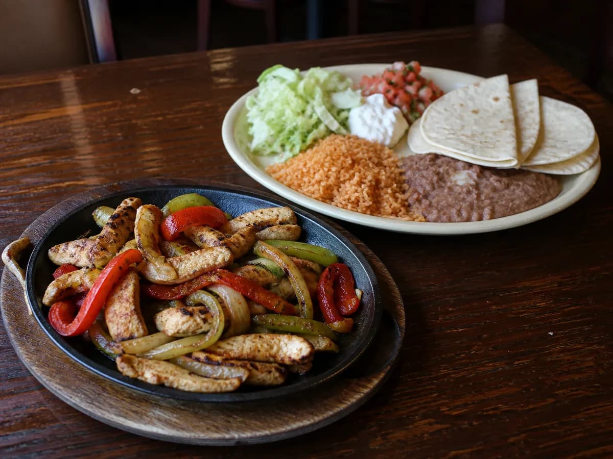 Lunch fajitas with grilled meat, peppers, onions, rice, and beans